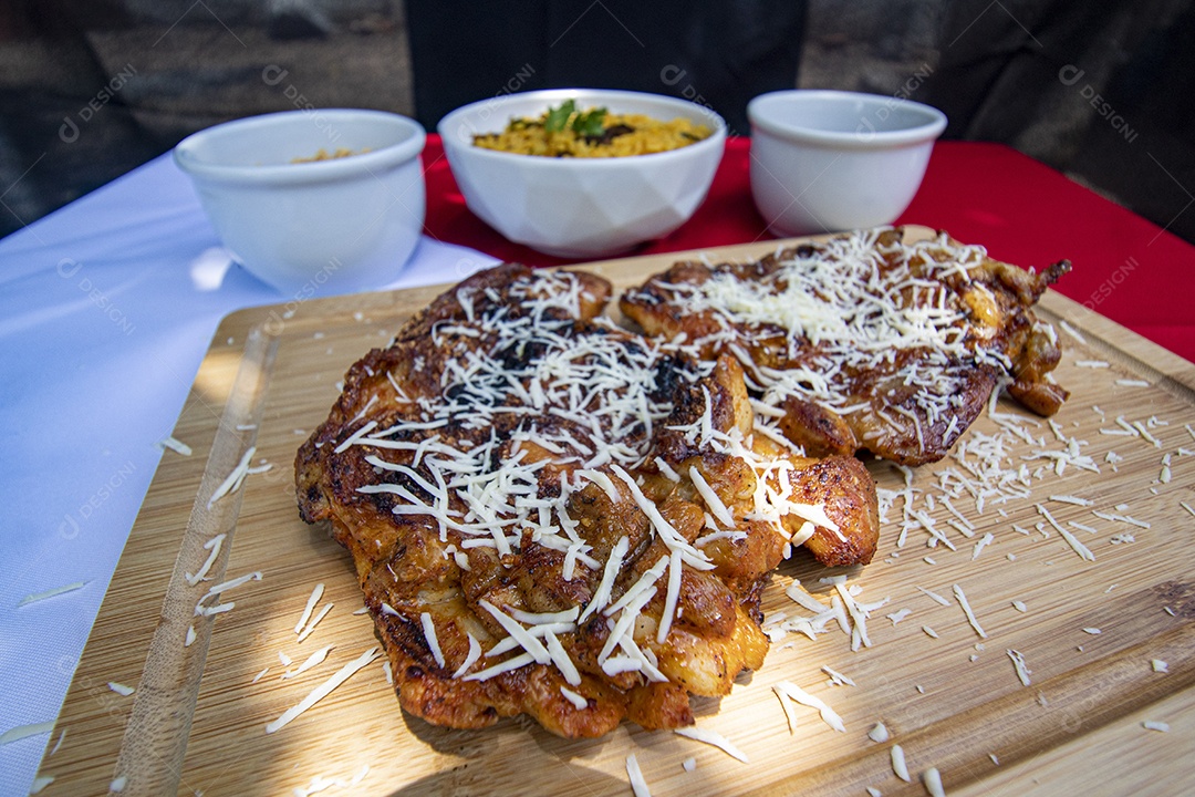 Carne assada suculenta com queijo servida em um prato branco com acompanhamentos
