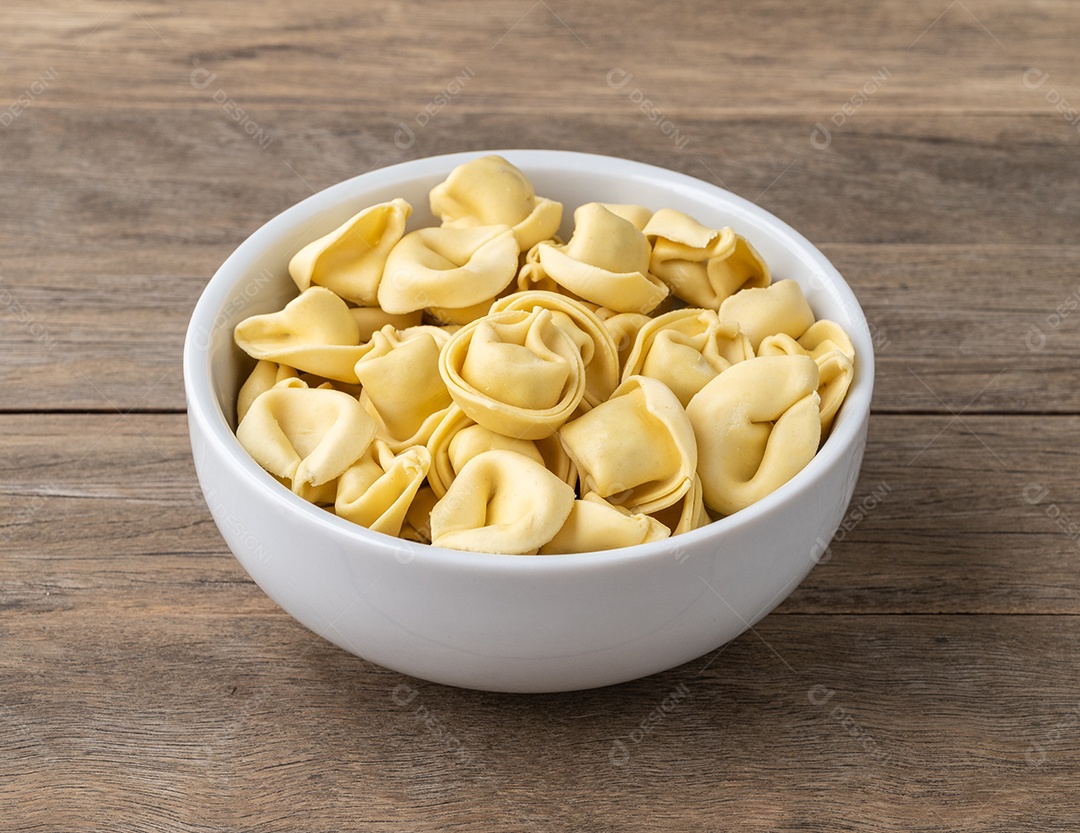 Cappelletti cru ou tortellini em uma tigela sobre a mesa de madeira.