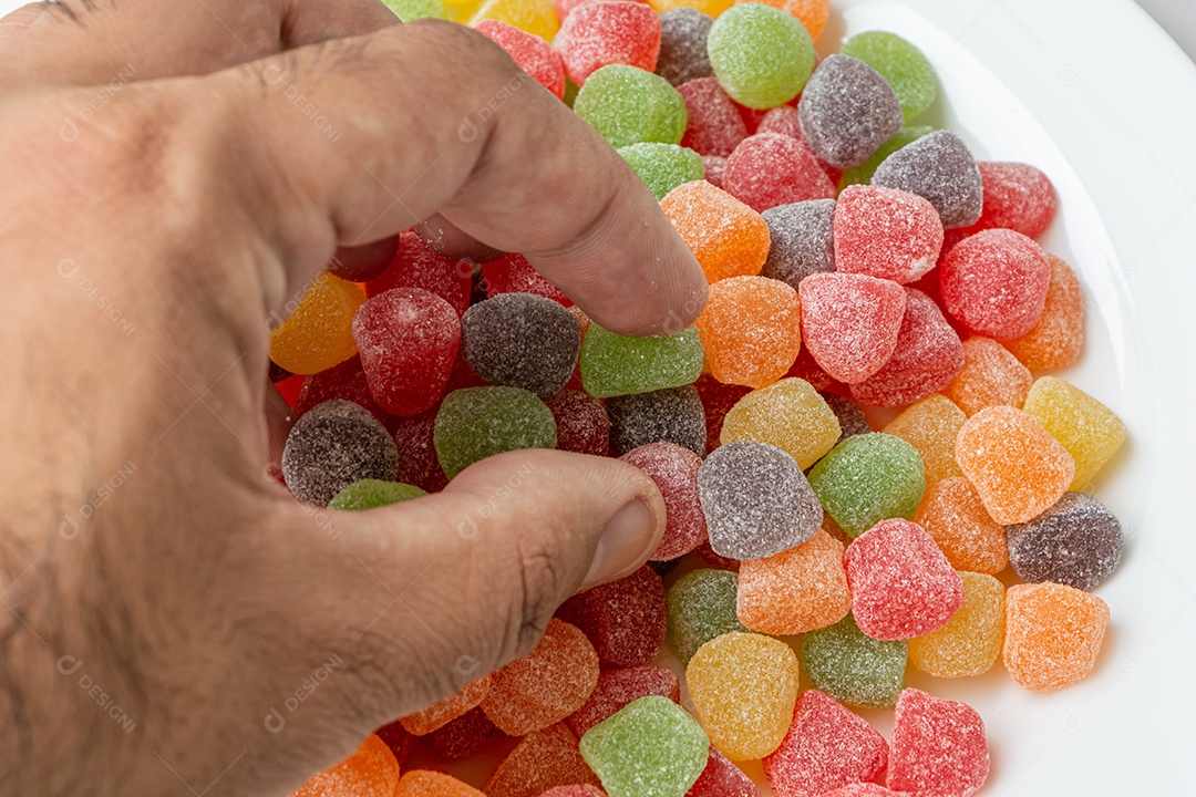 mão masculina pegando gotas de goma coloridas