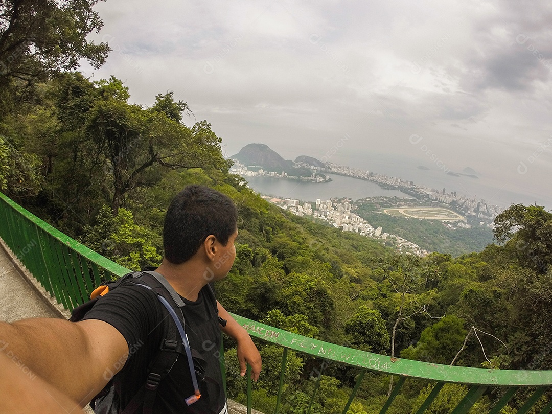 homem curtindo o visual das paineiras no parque nacional da tijuca com a lagoa rodrigo de freitas e a praia de ipanema ao fundo no Rio de Janeiro.