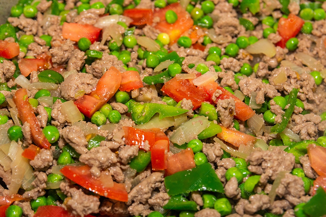 carne picada, ervilha, pimentão verde e tomate picado em uma panela no Brasil.