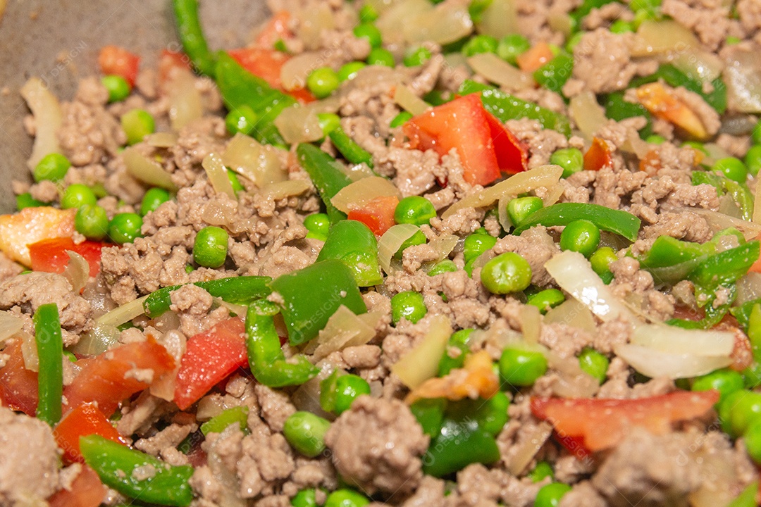 carne picada, ervilha, pimentão verde e tomate picado em uma panela no Brasil.