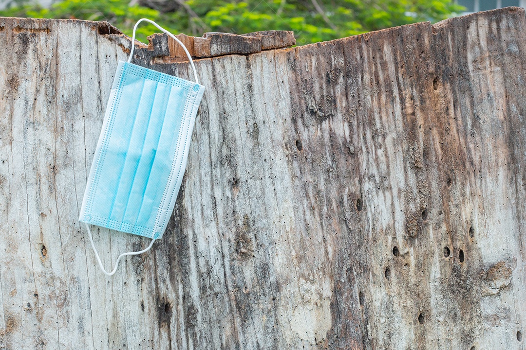 máscara de proteção descartável azul, usada para proteção contra cornavírus, jogada em um tronco de árvore no Rio de Janeiro.