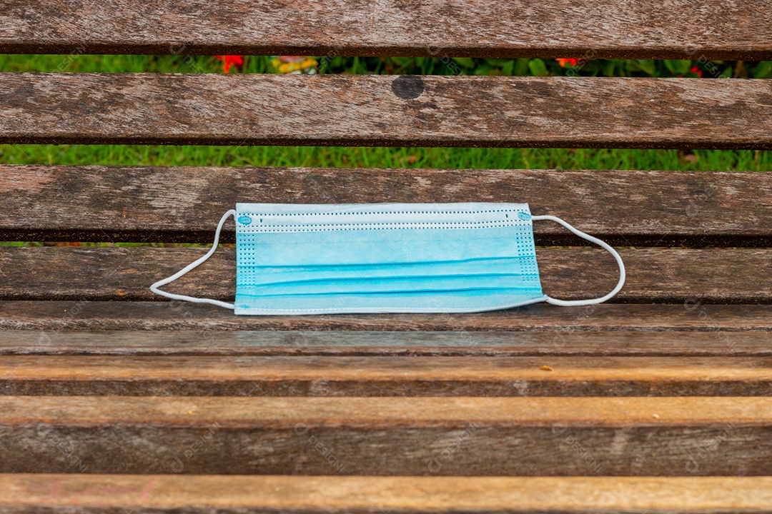 máscara protetora descartável azul, usada para proteção contra o cornavírus, jogada em uma bancada de madeira no Rio de Janeiro.