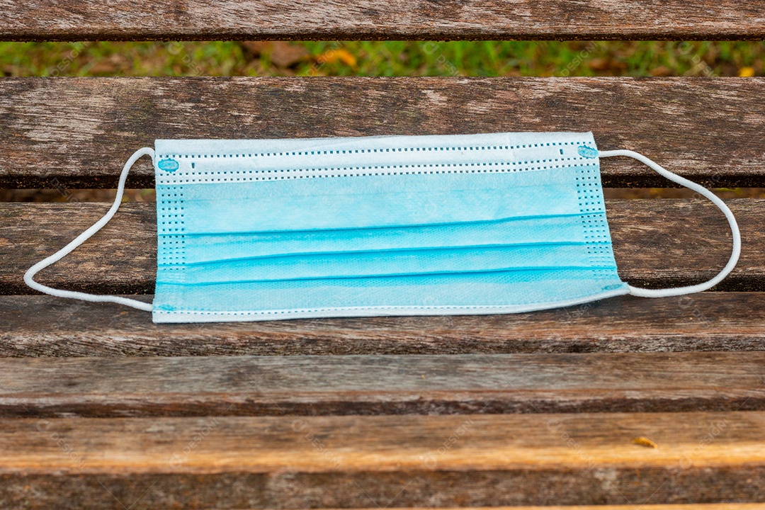 máscara protetora descartável azul, usada para proteção contra o cornavírus, jogada em uma bancada de madeira no Rio de Janeiro.