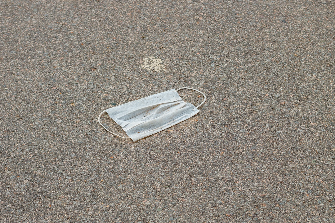 máscara protetora descartável azul, usada para proteção contra o cornavírus, jogada no asfalto do Rio de Janeiro.