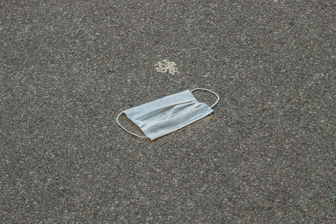 máscara protetora descartável azul, usada para proteção contra o cornavírus, jogada no asfalto do Rio de Janeiro.