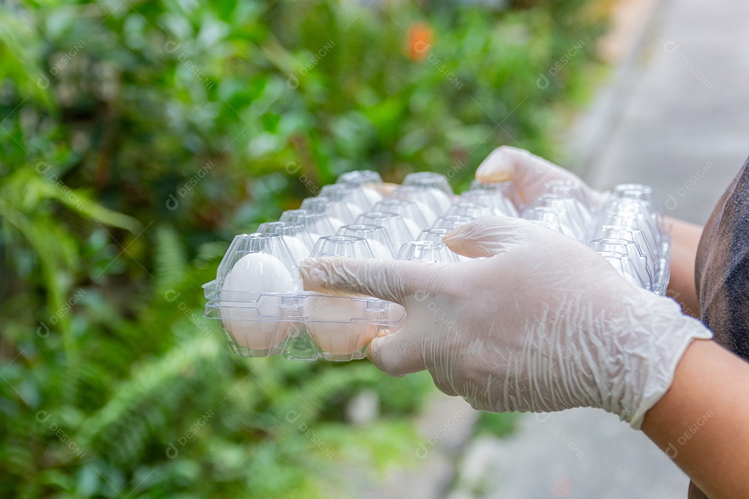 mulher branca segurando caixa de ovos com luva para se proteger do coronavírus no Rio de Janeiro.