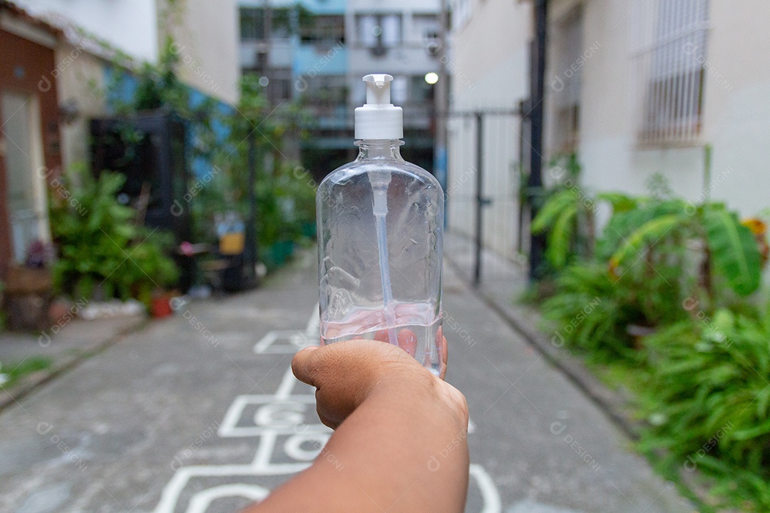 mão de homem moreno segurando uma garrafa de álcool gel para proteção contra coronavírus no Rio de Janeiro.