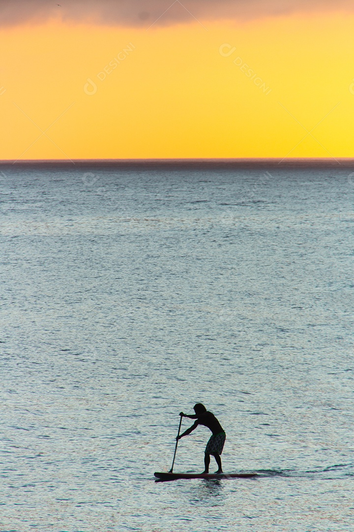 silhueta de homem com seu stand up paddle com um belo fundo por do sol na praia de Ipanema. no Rio de Janeiro.