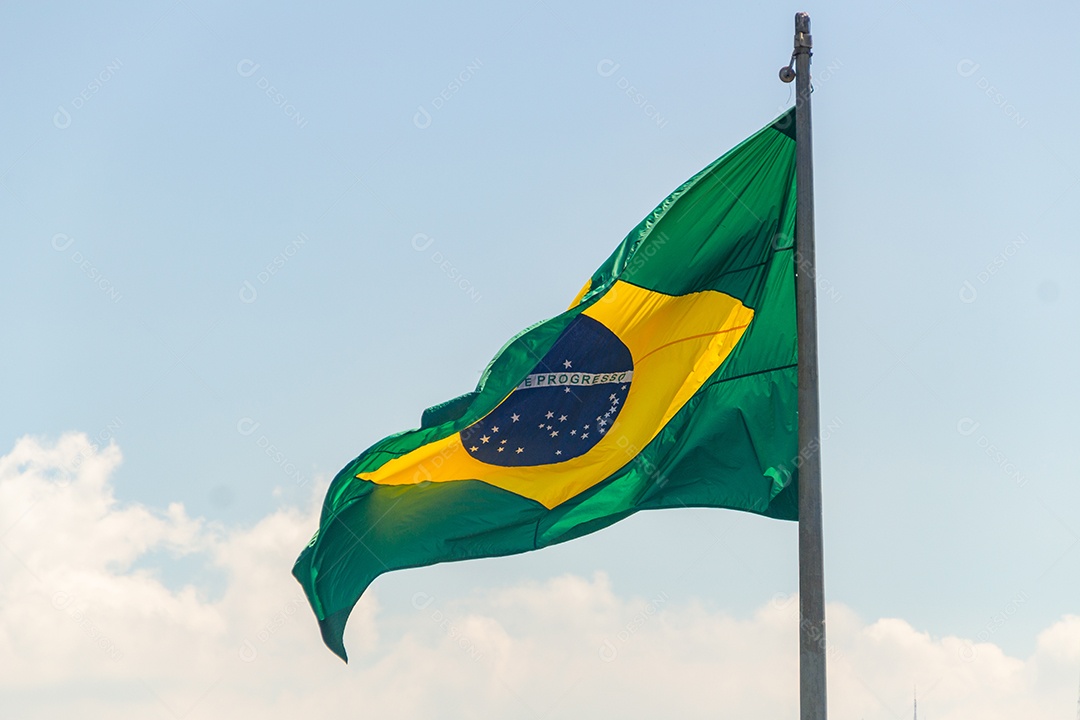 Bandeira brasileira voando com fundo de céu azul no Rio de Janeiro.