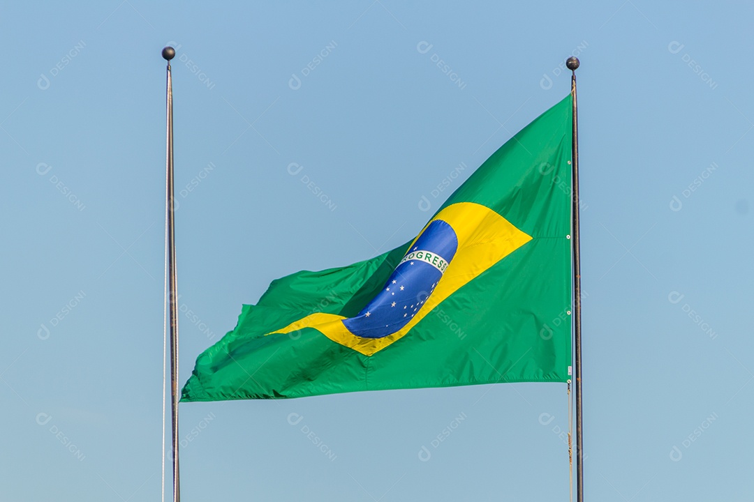 Bandeira brasileira voando com fundo de céu azul no Rio de Janeiro.