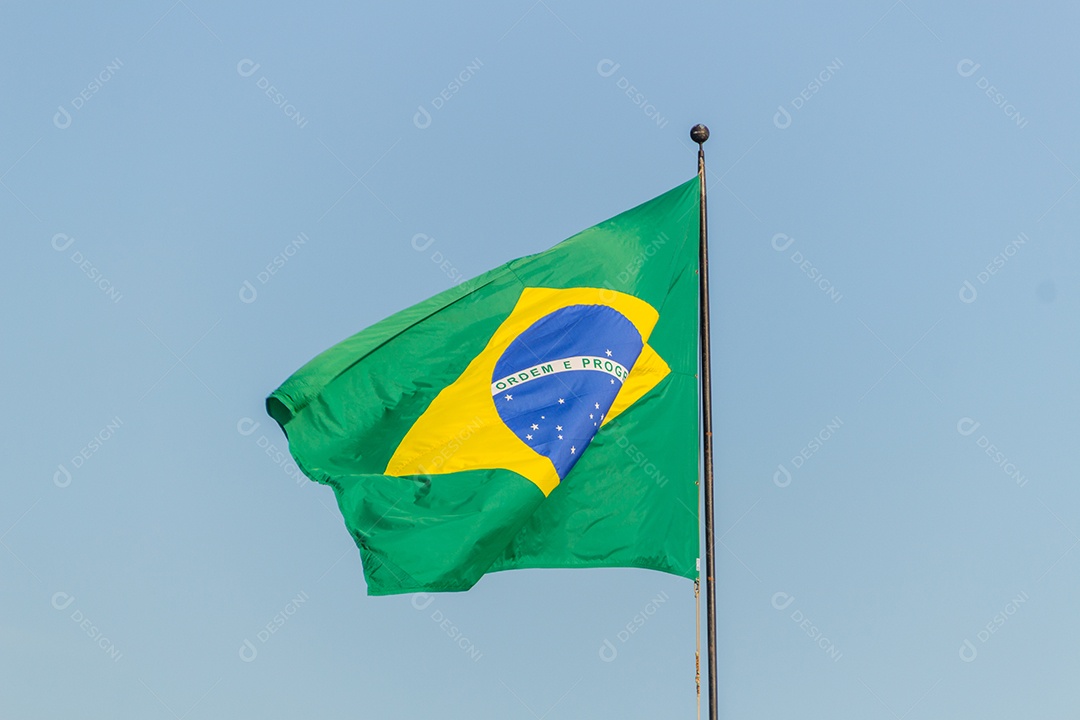 Bandeira brasileira voando com fundo de céu azul no Rio de Janeiro.