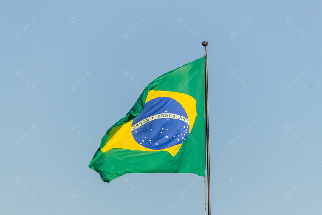 Bandeira brasileira voando com fundo de céu azul no Rio de Janeiro.