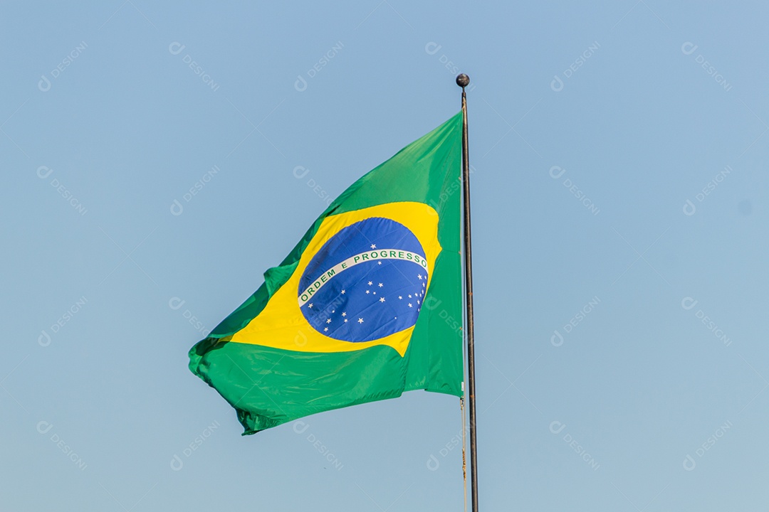 Bandeira brasileira voando com fundo de céu azul no Rio de Janeiro.