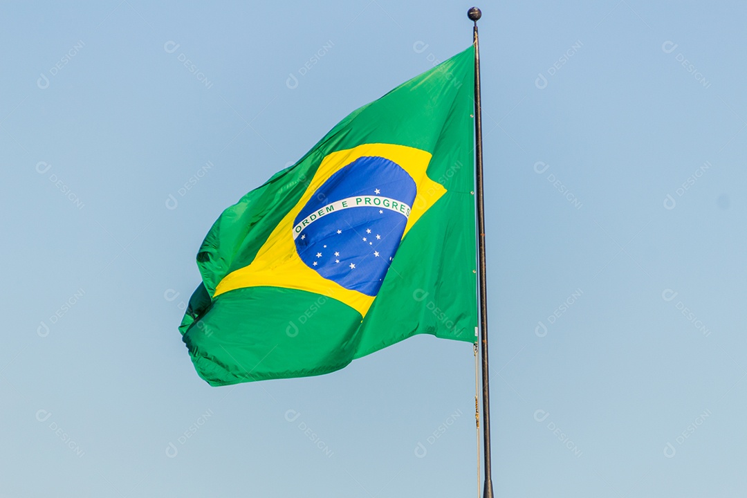 Bandeira brasileira voando com fundo de céu azul no Rio de Janeiro.