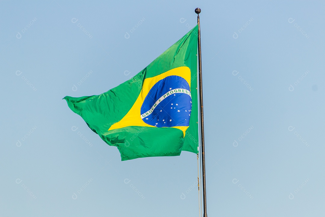 Bandeira brasileira voando com fundo de céu azul no Rio de Janeiro.