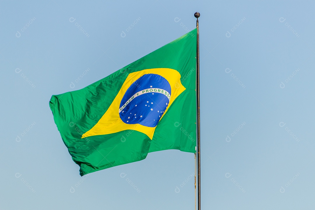 Bandeira brasileira voando com fundo de céu azul no Rio de Janeiro.
