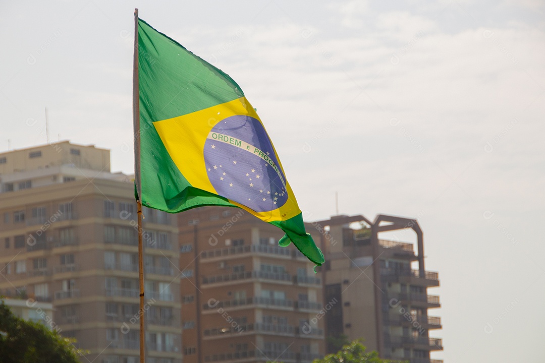 bandeira do brasil ao ar livre com prédios ao fundo no brasil.