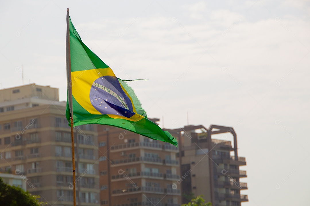bandeira do brasil ao ar livre com prédios ao fundo no brasil.