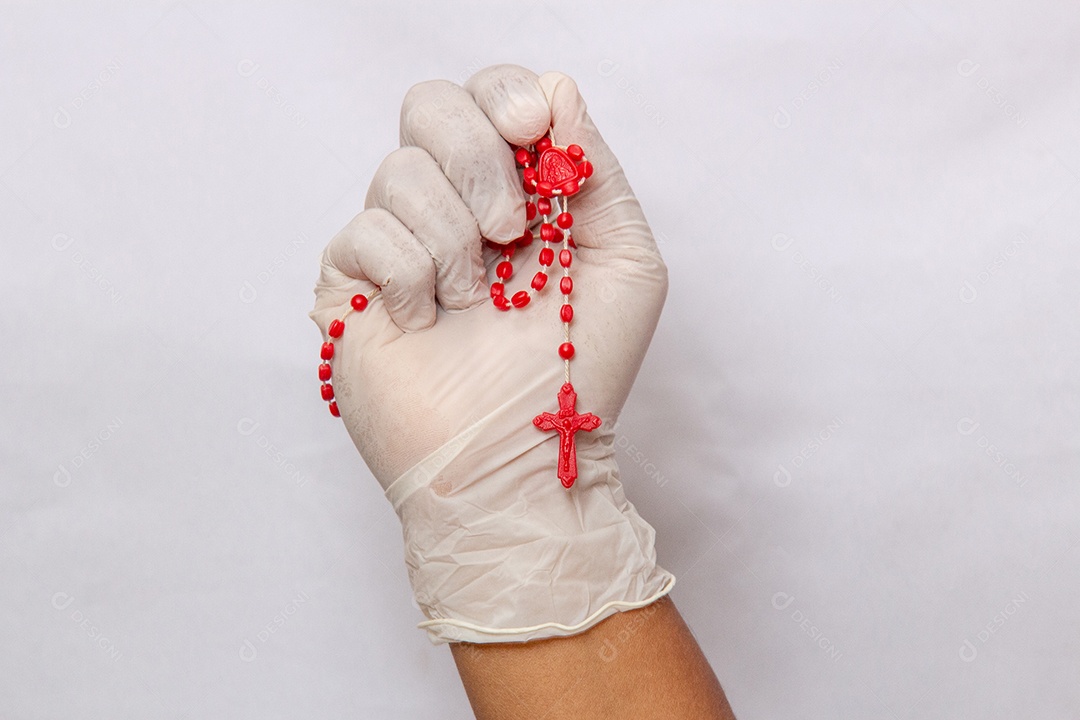 mãos enluvadas brancas segurando um terço vermelho, proteção contra coronavírus no Brasil.