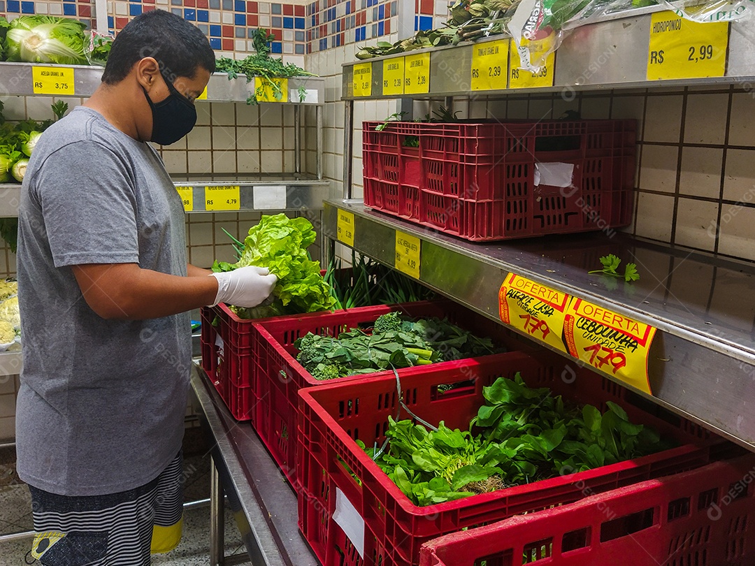 Homem negro escolhendo alface com luva, proteção contra coronavírus no Brasil