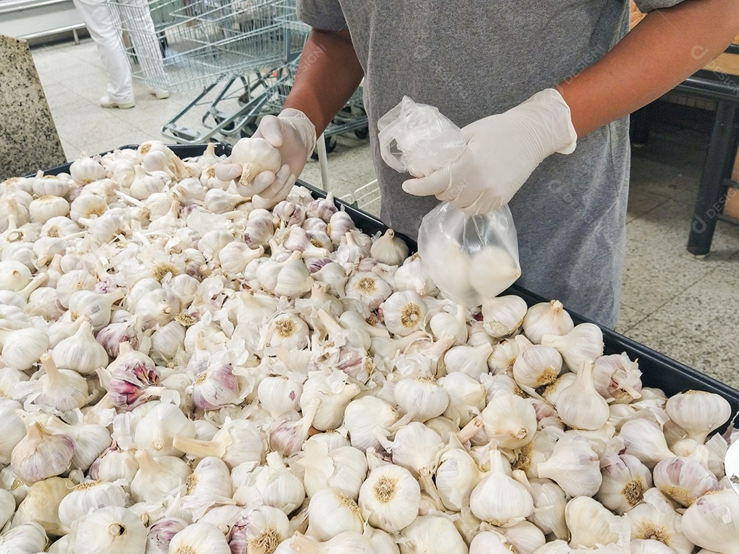 mãos negras de um homem escolhendo alho com luva, proteção contra coronavírus no Brasil.