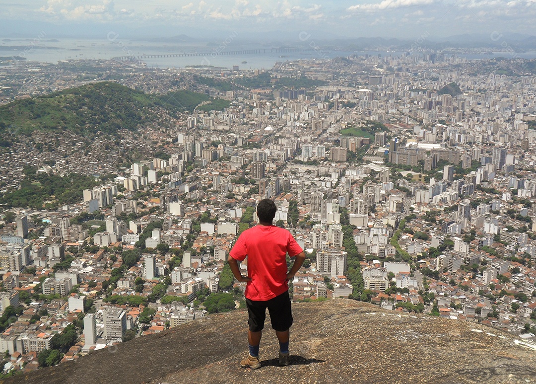 homem admirando a vista da cidade do rio de janeiro do alto da pedra dos perdidos ( pico do perdido ) no bairro do grajau.