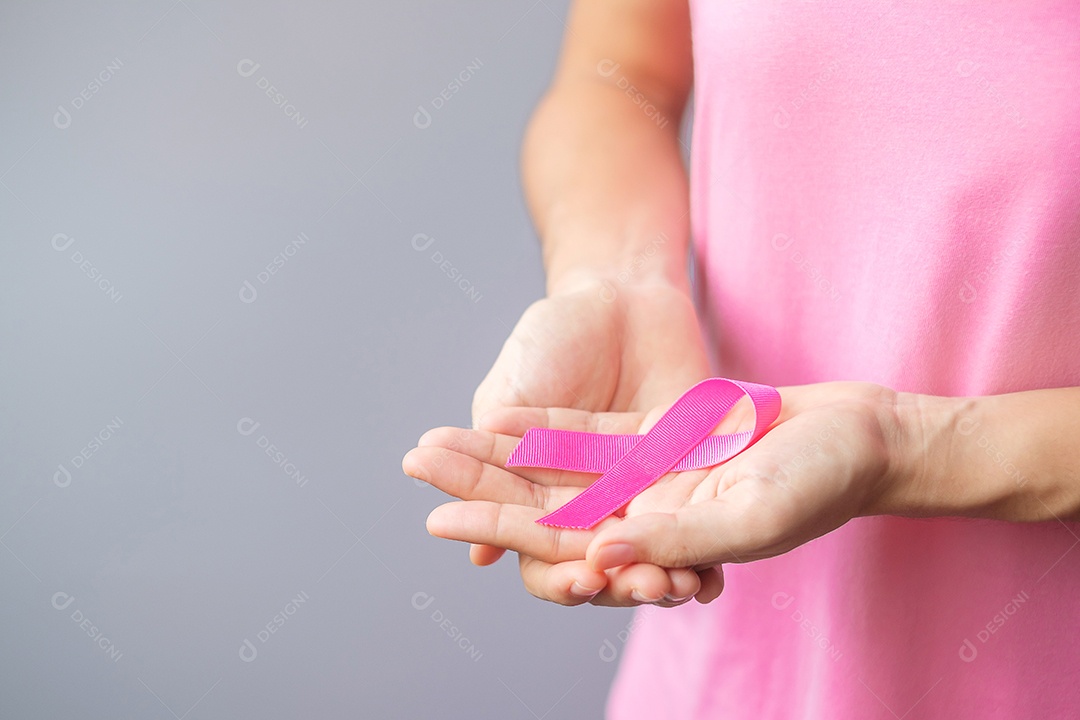 Outubro Mês de conscientização do câncer de mama, idosa Mulher de camiseta rosa com a mão segurando a fita rosa para apoiar as pessoas que vivem e estão doentes.