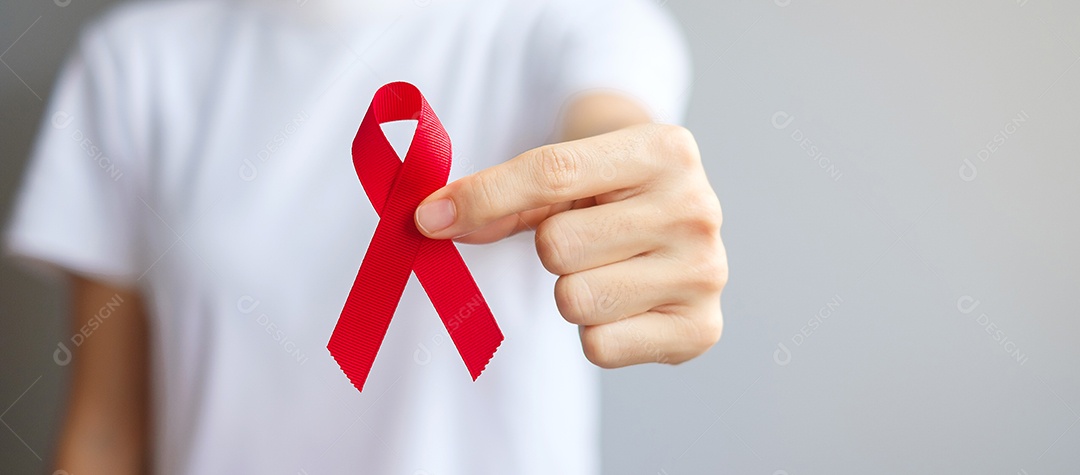 Mão segurando a fita vermelha para dezembro Dia Mundial da Aids (síndrome da imunodeficiência adquirida), mês de conscientização do câncer de mieloma múltiplo e semana nacional da fita vermelha.
