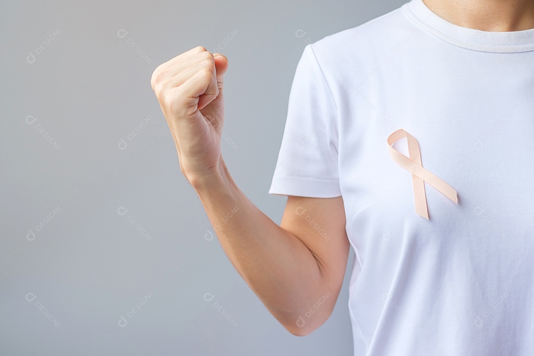 Mão de uma mulher segurando a fita de pêssego para o mês de conscientização do câncer uterino de setembro. Conceito de saúde e dia mundial do câncer