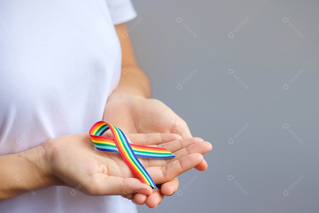 Mão segurando a fita LGBTQ Rainbow para apoiar a comunidade Lésbica, Gay, Bissexual, Transgênero e Queer e o conceito do mês do orgulho