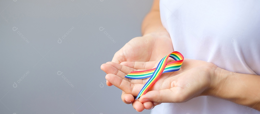 Mão segurando a fita LGBTQ Rainbow para apoiar a comunidade Lésbica, Gay, Bissexual, Transgênero e Queer e o conceito do mês do orgulho