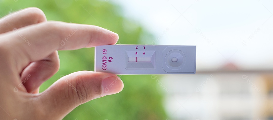 Homem segurando o kit de teste rápido de antígeno com resultado negativo durante o teste de cotonete COVID-19. Coronavírus Self nasal ou Teste em casa, conceito de bloqueio e isolamento doméstico
