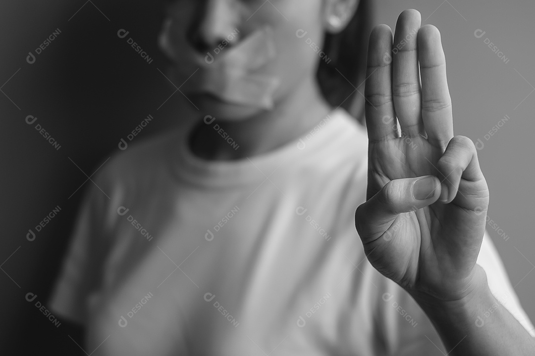 Mulher mostra três dedos com a boca selada com fita adesiva.