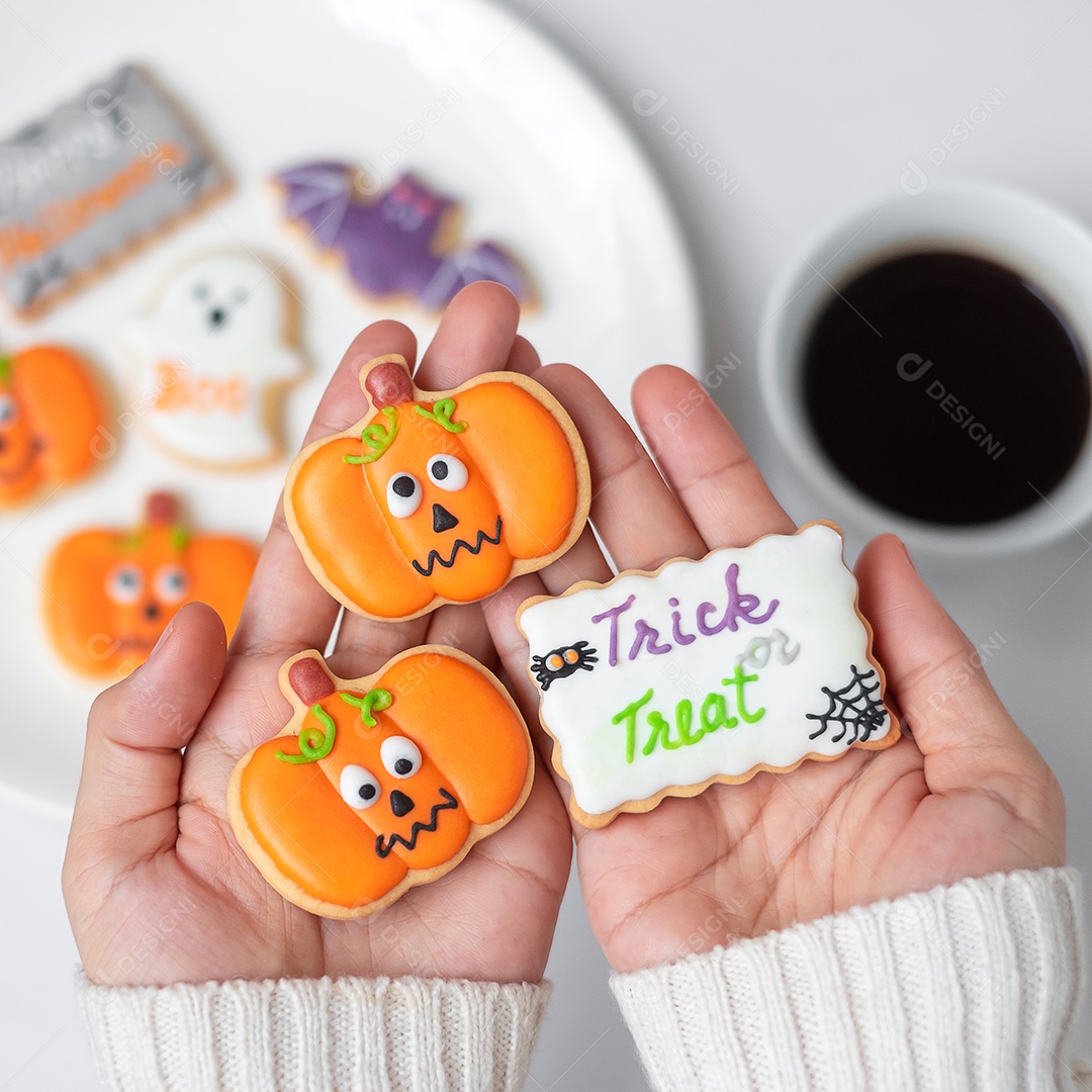 Mão de mulher segurando engraçado Halloween Cookie durante o café. Feliz dia de Halloween, truque ou ameaça, Olá outubro, outono outono, tradicional, festa e conceito de férias