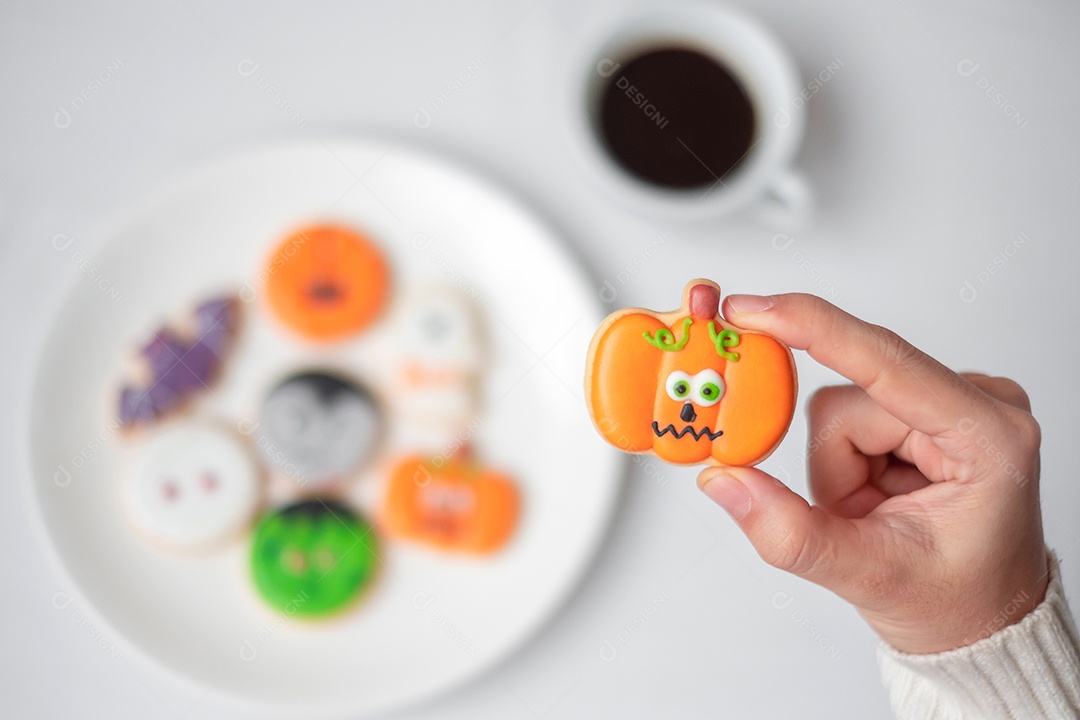 Mão de mulher segurando engraçado Halloween Cookie durante o café. Feliz dia de Halloween, truque ou ameaça, Olá outubro, outono outono, tradicional, festa e conceito de férias