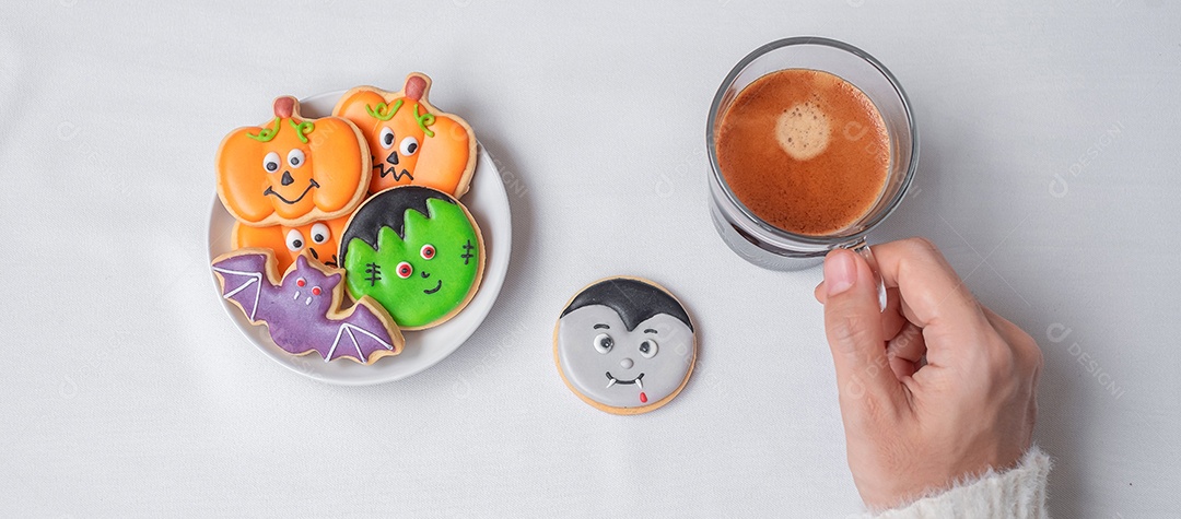 Mão de uma mulher segurando a xícara de café durante comer biscoitos engraçados de Halloween. Feliz dia de Halloween, truque ou ameaça, Olá outubro, outono outono, tradicional, festa e conceito de férias