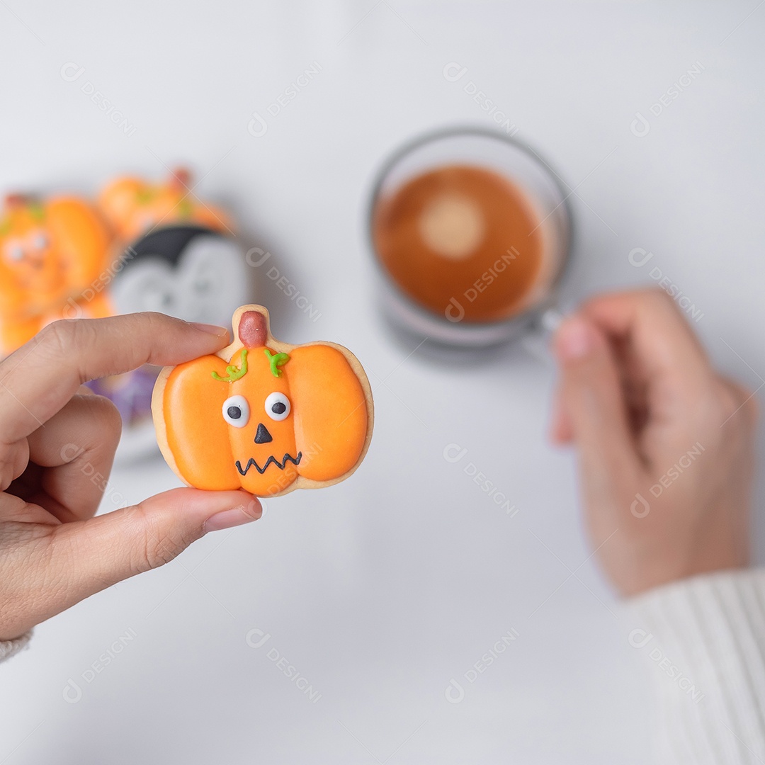 Mão de mulher segurando engraçado Halloween Cookie durante o café. Feliz dia de Halloween, truque ou ameaça, Olá outubro, outono outono, tradicional, festa e conceito de férias