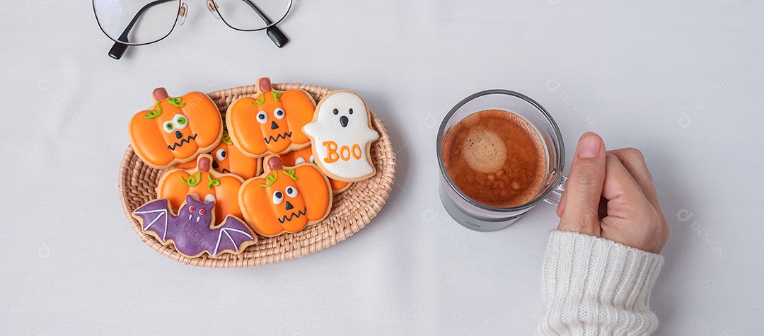 Mão de uma mulher segurando a xícara de café durante comer biscoitos engraçados de Halloween. Feliz dia de Halloween, truque ou ameaça, Olá outubro, outono outono, tradicional, festa e conceito de férias