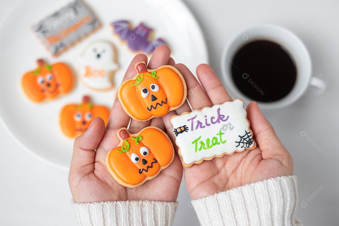Mão de mulher segurando engraçado biscoito de Halloween durante o café.