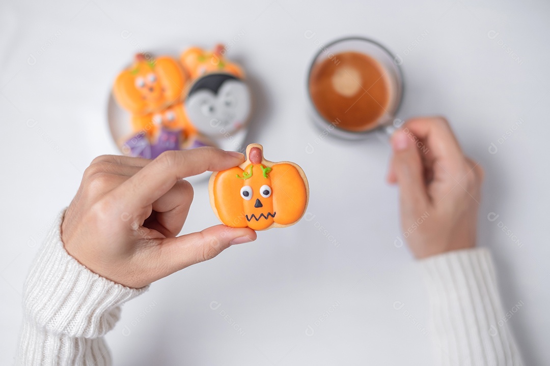 Mão de mulher segurando engraçado biscoito de Halloween durante o café.