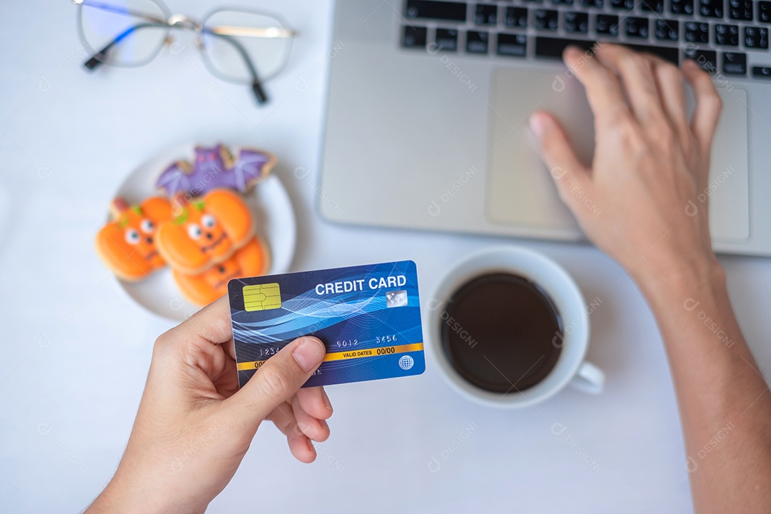 Mão segurando o cartão de crédito para compras on-line no laptop durante.