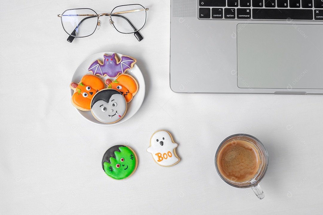 Biscoitos de Halloween, café quente e laptop de computador na parte traseira branca