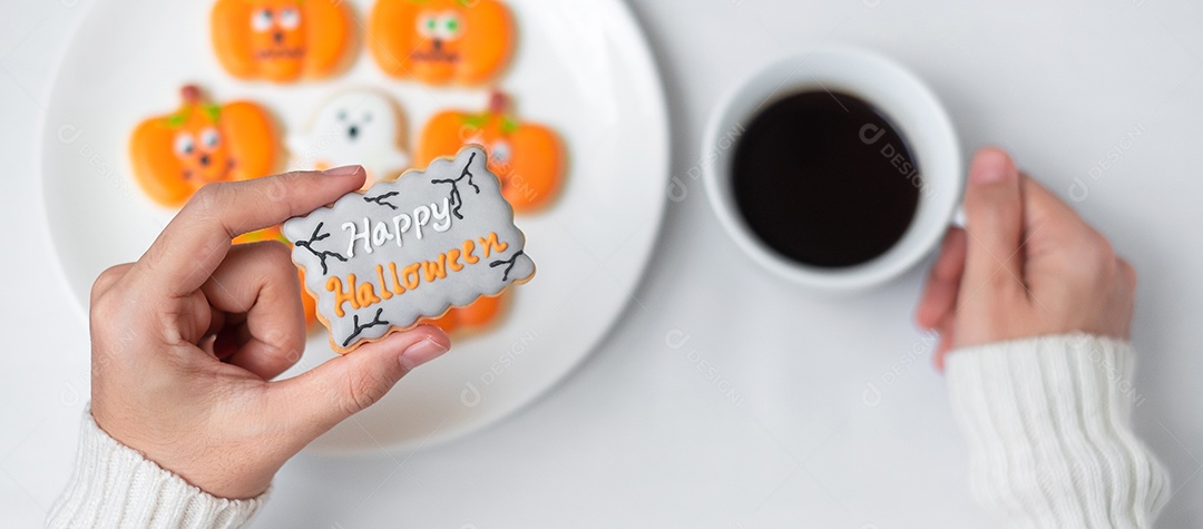 Mão de mulher segurando engraçado Halloween Cookie durante o café. Feliz dia de Halloween, truque ou ameaça, Olá outubro, outono outono, tradicional, festa e conceito de férias