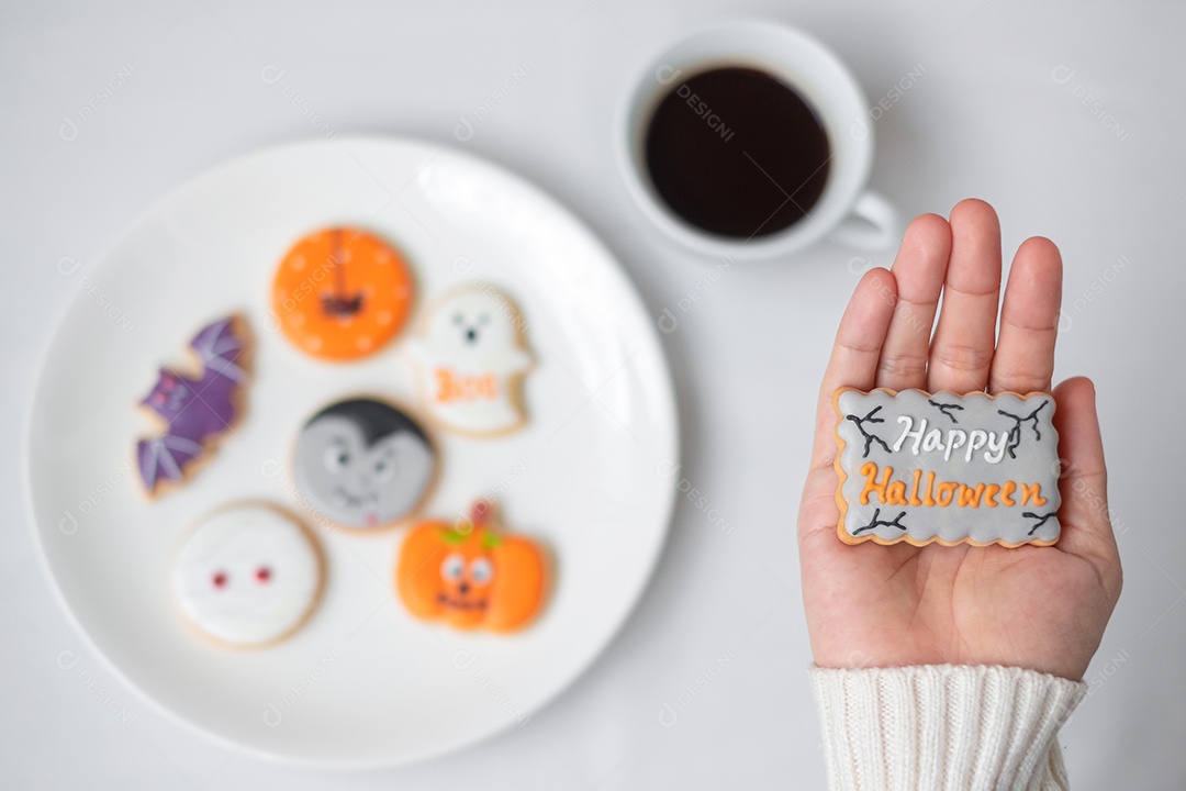 Mão de mulher segurando engraçado Halloween Cookie durante o café. Feliz dia de Halloween, truque ou ameaça, Olá outubro, outono outono, tradicional, festa e conceito de férias