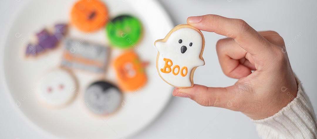 Mão de mulher segurando engraçado Halloween Cookie durante o café. Feliz dia de Halloween, truque ou ameaça, Olá outubro, outono outono, tradicional, festa e conceito de férias