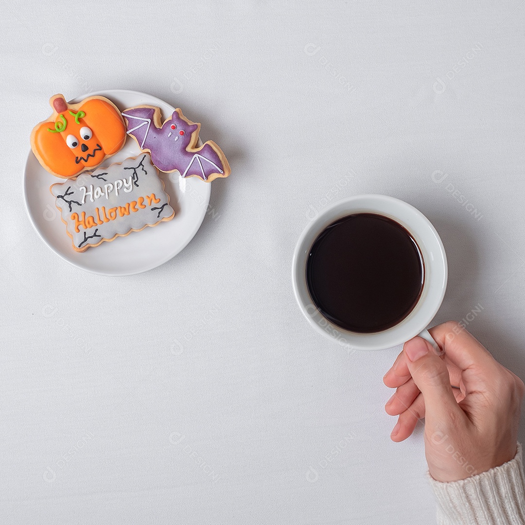 Mão de uma mulher segurando a xícara de café durante comer biscoitos engraçados de Halloween. Feliz dia de Halloween, truque ou ameaça, Olá outubro, outono outono, tradicional, festa e conceito de férias