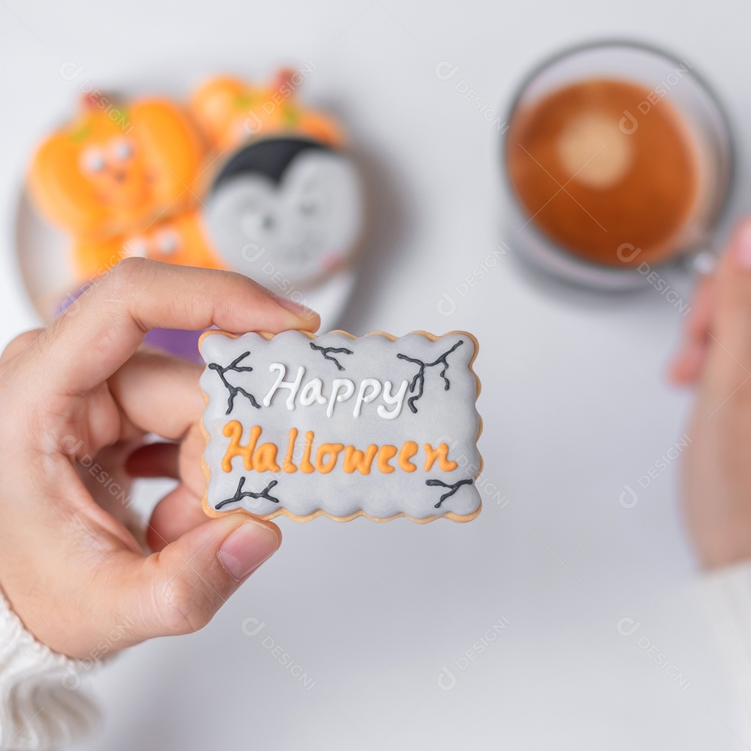 Mão de mulher segurando engraçado Halloween Cookie durante o café. Feliz dia de Halloween, truque ou ameaça, Olá outubro, outono outono, tradicional, festa e conceito de férias