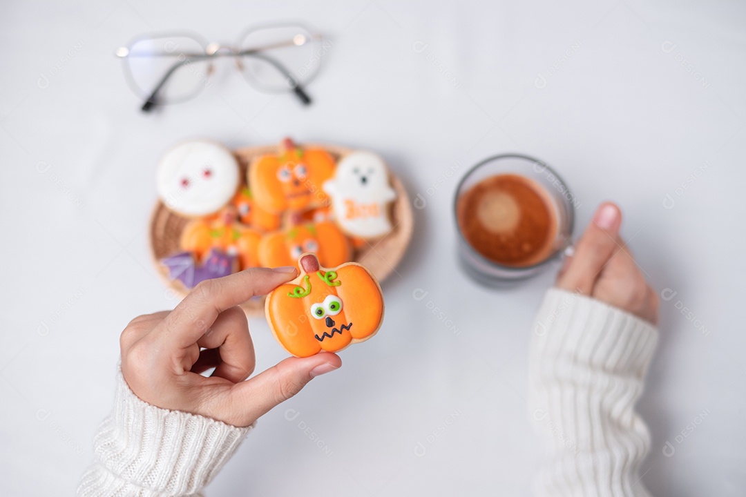 Mão de mulher segurando engraçado Halloween Cookie durante o café. Feliz dia de Halloween, truque ou ameaça, Olá outubro, outono outono, tradicional, festa e conceito de férias